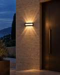Sella slim black up and down wall light on a covered walkway wall, throwing a narrow beam up and down the plaster