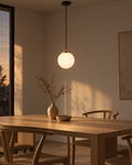Orbe glass globe pendant on a matte black stem against a white ceiling, the globe appearing to float