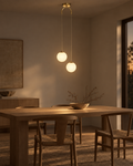 Orbe twin glass globe pendant in brass, two staggered globes lighting a kitchen island at dusk