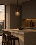 Velo smoke grey glass pendant above a dining table, the tinted shade hiding the bulb