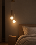Lira twin brass bedside pendant with two staggered shades above a bed from one ceiling point