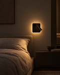 Lume rectangular matte black reading sconce casting a horizontal band of light above a wide headboard